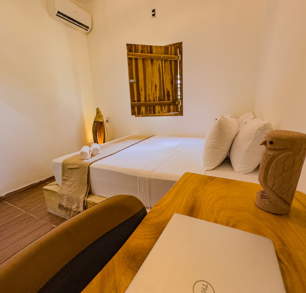 Cama da Suíte Neblina com janela de madeira entreaberta e ar-condicionado