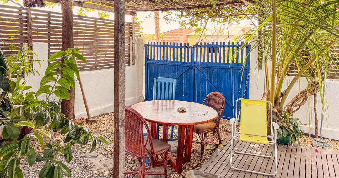 Área externa da Casa Mareser com mesa, cadeiras e jardim sob pergolado