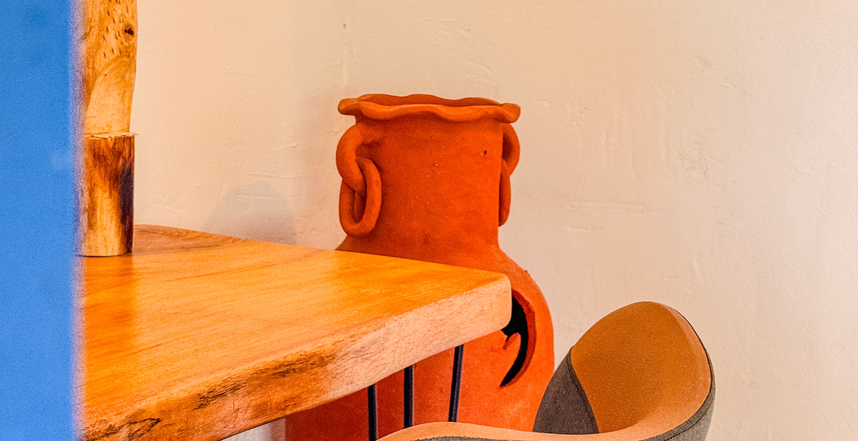 Vaso de cerâmica artesanal sobre mesa de madeira em uma das suítes da Casa Mareser
