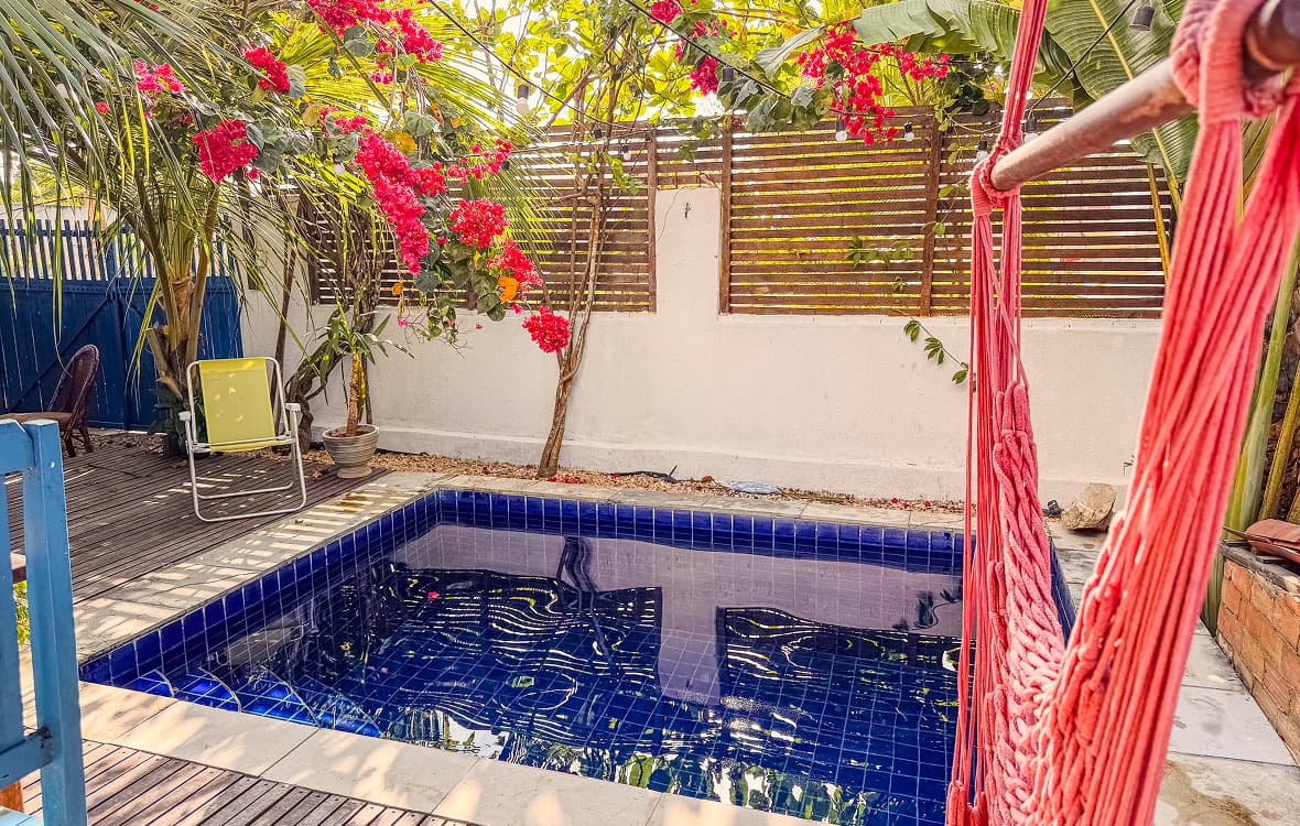 Piscina da Casa Mareser cercada por primaveras e rede de descanso